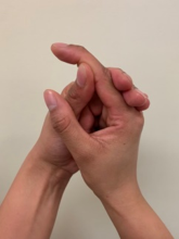 A photograph of a persons hands held up, holding the middle joint of the finger to bend and straighten the tip of your finger