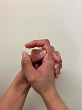 A photograph of a persons hands held up, support the base of the finger, bend and straighten the middle joint of thefinger, making sure the knuckle at the base of the finger remains still