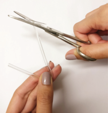 A photograph of the person cutting the end of new tubing to make a thin point