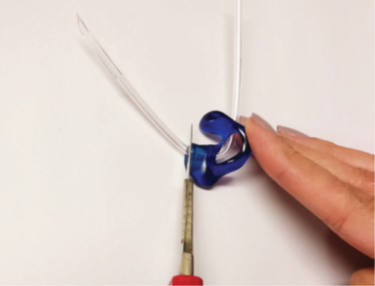 A photograph of the person using scissors to cut the tapered end off as close to the mould as possible
