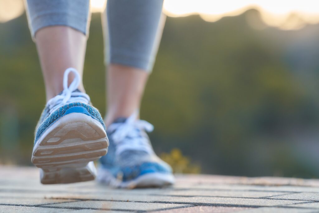 A view of someone's feet walking along the pavement in exercise leggings.