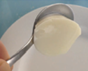 A photograph of a spoon holding thick puree